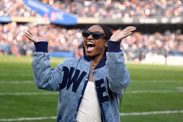 Simone Biles waves to the crowd during halftime of a game