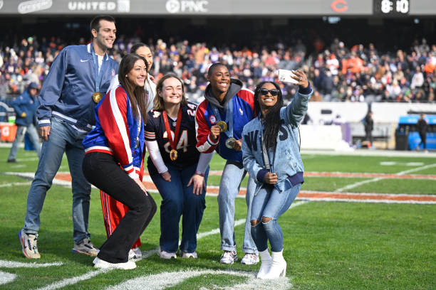  Simone Biles (R) and other Olympians from Illinois take a selfie on the field during halftime of a game 