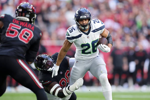 Zach Charbonnet #26 of the Seattle Seahawks runs with the ball while being tackled by Naquan Jones